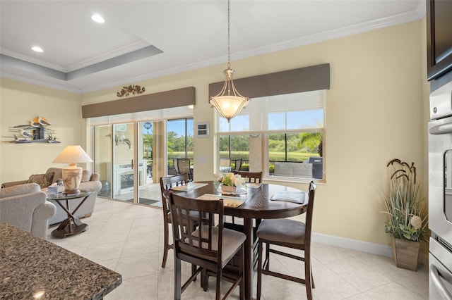 tiled dining area with a raised ceiling and crown molding