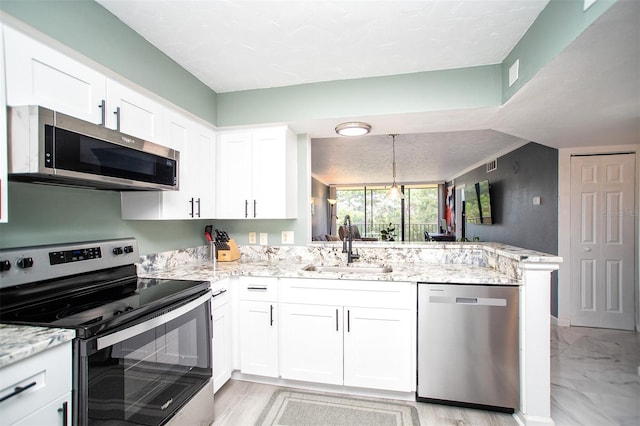 kitchen featuring appliances with stainless steel finishes, white cabinets, kitchen peninsula, and light stone countertops