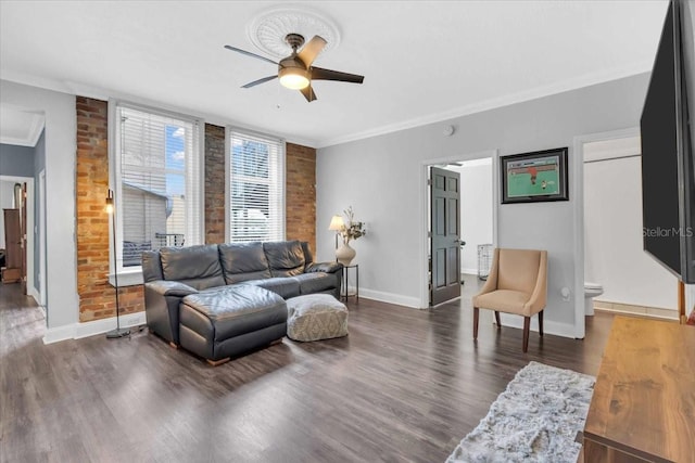 living room featuring ceiling fan, dark wood-type flooring, brick wall, and crown molding