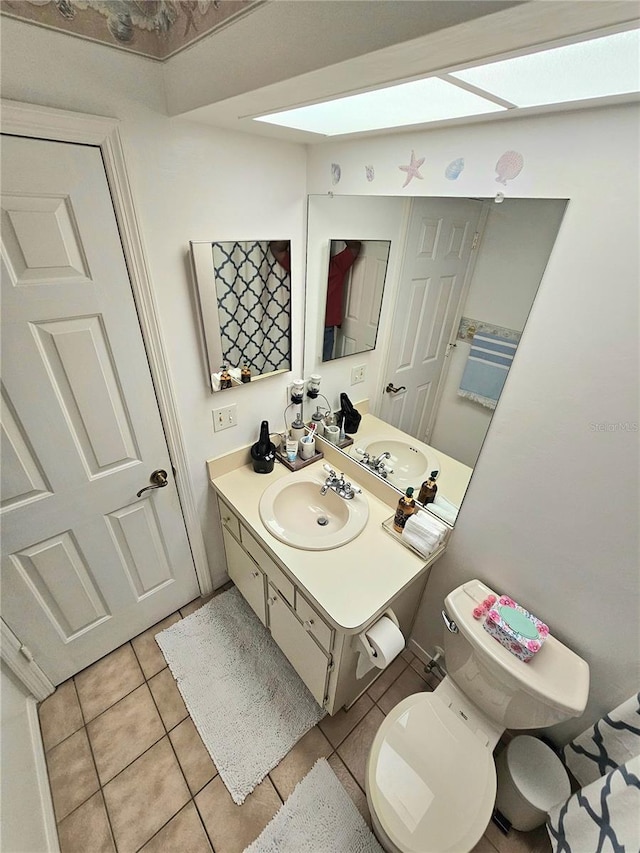 bathroom featuring a skylight, vanity, toilet, and tile patterned floors