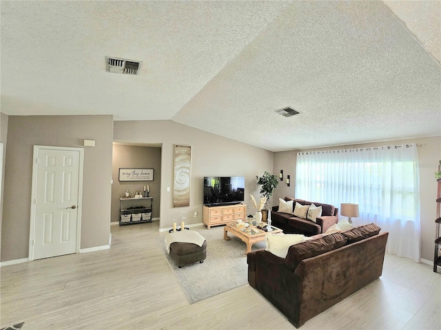 living room with vaulted ceiling, light hardwood / wood-style floors, and a textured ceiling