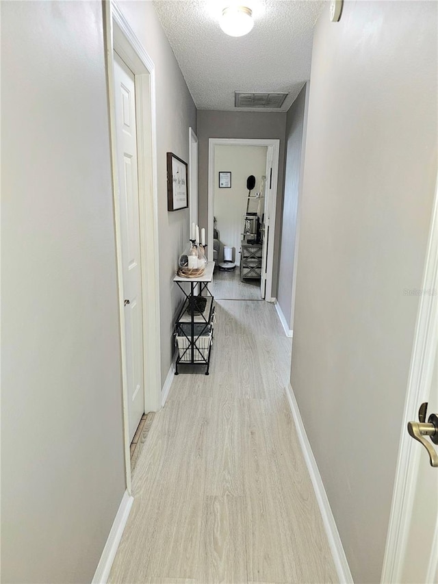 hall featuring a textured ceiling and light wood-type flooring