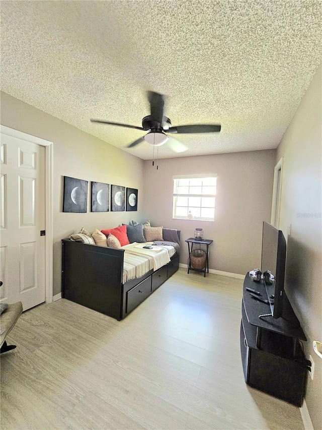 bedroom featuring ceiling fan, hardwood / wood-style floors, and a textured ceiling