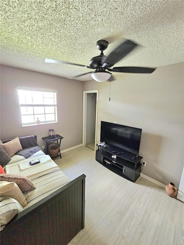 living room featuring ceiling fan, a textured ceiling, and light hardwood / wood-style floors