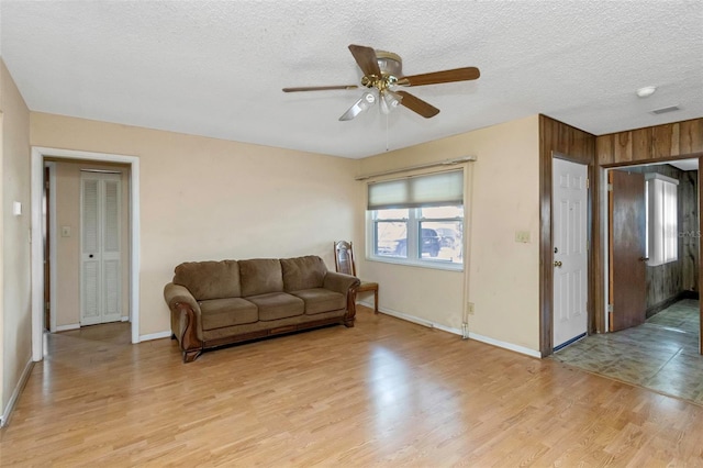 living room with a textured ceiling, light wood-type flooring, and ceiling fan