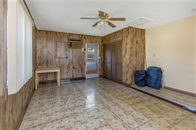 empty room with ceiling fan, wood walls, a wall mounted air conditioner, and tile patterned flooring