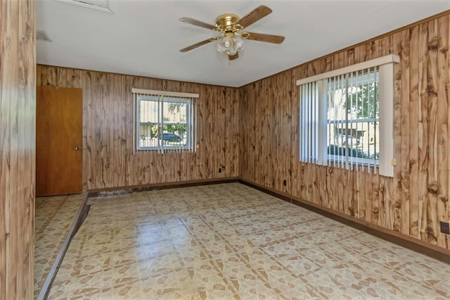 unfurnished room featuring wood walls, tile patterned floors, and ceiling fan