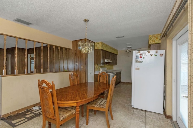 tiled dining room with ceiling fan with notable chandelier and a textured ceiling