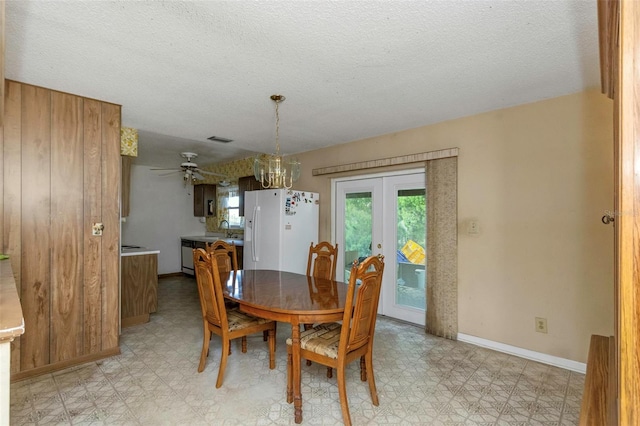 tiled dining area with french doors, sink, a textured ceiling, and ceiling fan with notable chandelier