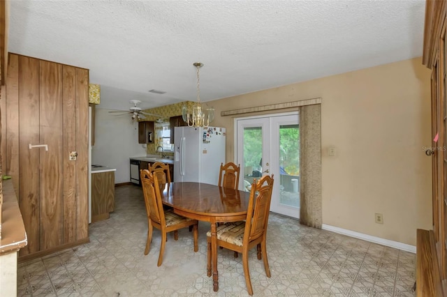 dining area with sink, a textured ceiling, ceiling fan with notable chandelier, and french doors