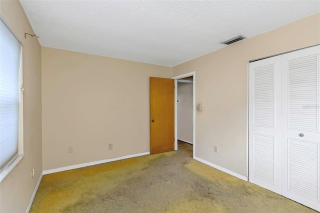 unfurnished bedroom with a textured ceiling, light carpet, and a closet