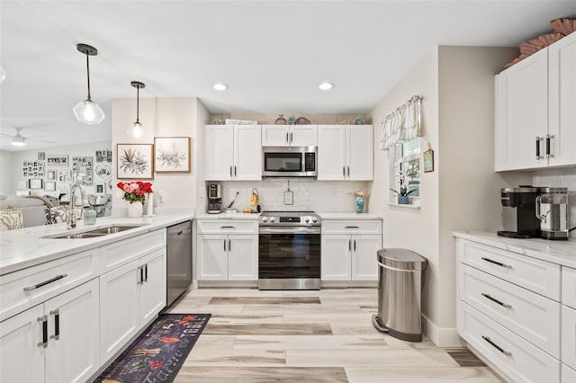 kitchen with appliances with stainless steel finishes, white cabinetry, and a sink