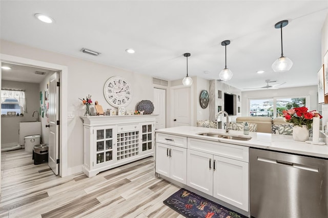 kitchen featuring light stone counters, light hardwood / wood-style floors, stainless steel dishwasher, white cabinetry, and pendant lighting