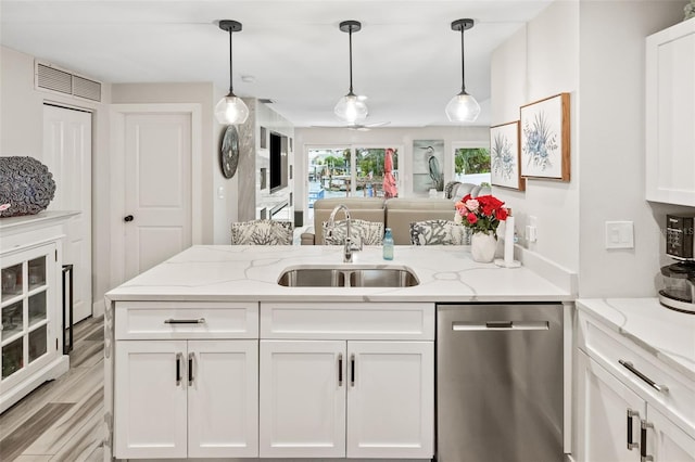 kitchen with stainless steel dishwasher, white cabinets, light stone countertops, sink, and decorative light fixtures