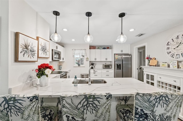 kitchen featuring kitchen peninsula, stainless steel appliances, a breakfast bar, and white cabinetry