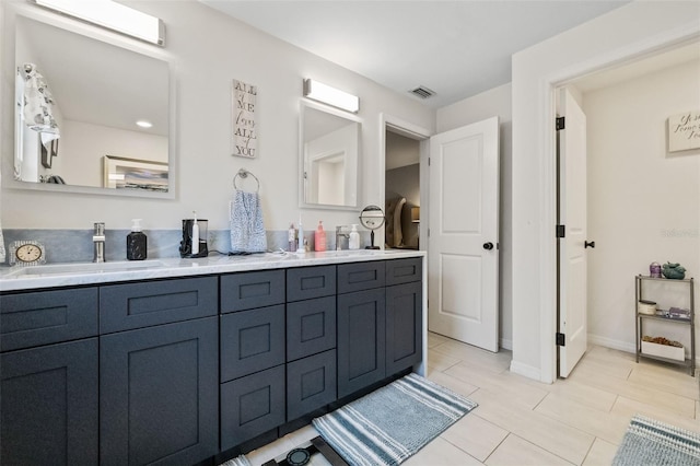 bathroom with double vanity, visible vents, baseboards, and a sink