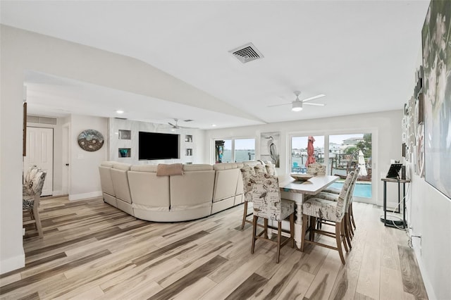 dining area with ceiling fan, vaulted ceiling, and light wood-type flooring