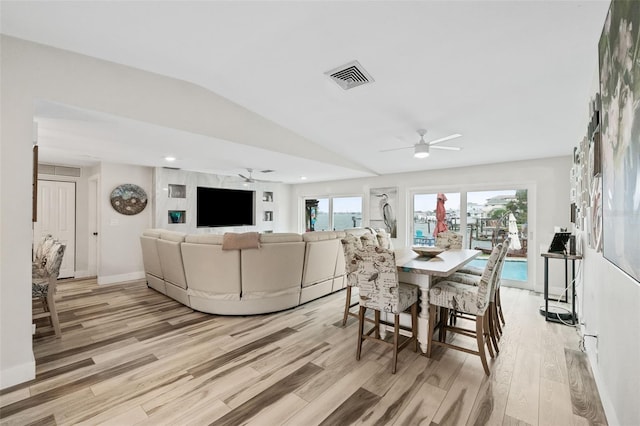 dining space featuring visible vents, light wood-type flooring, lofted ceiling, and a ceiling fan
