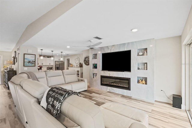 living area featuring wood finished floors, a ceiling fan, visible vents, recessed lighting, and a glass covered fireplace