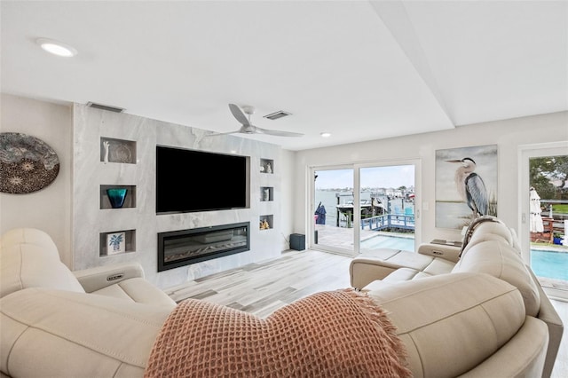 living room with ceiling fan, light wood-type flooring, and a fireplace