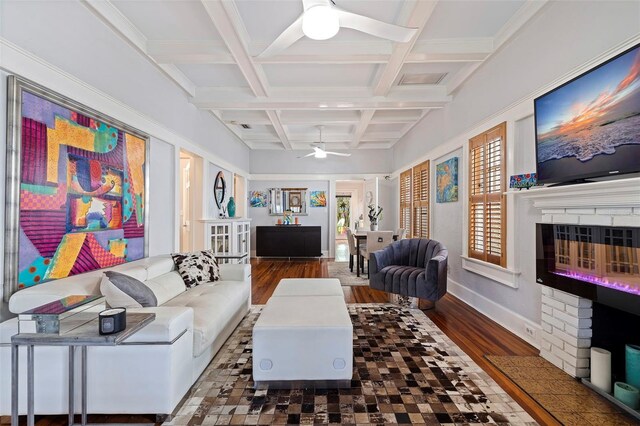 living room with coffered ceiling, beamed ceiling, ceiling fan, ornamental molding, and dark hardwood / wood-style floors