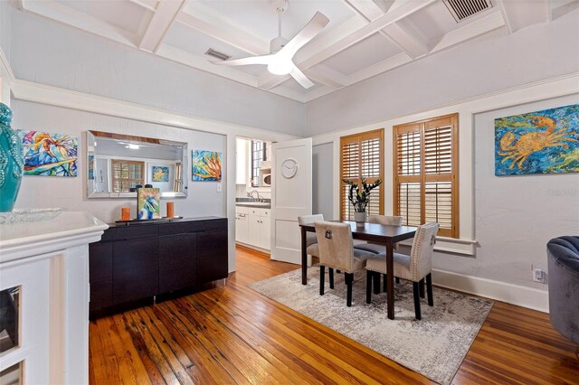 dining area with coffered ceiling, beam ceiling, ceiling fan, hardwood / wood-style flooring, and sink