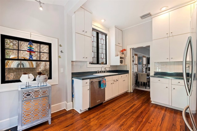 kitchen featuring a sink, dark countertops, backsplash, dark wood-style floors, and stainless steel appliances