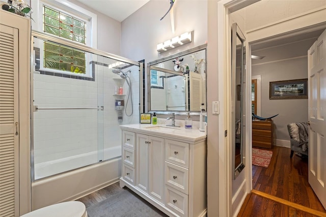 full bath with shower / bath combination with glass door, vanity, baseboards, and wood finished floors