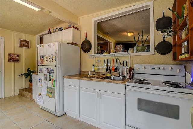 kitchen with sink, a textured ceiling, white cabinets, and white appliances