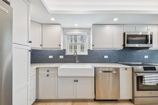 kitchen with decorative backsplash, stainless steel appliances, sink, and white cabinetry