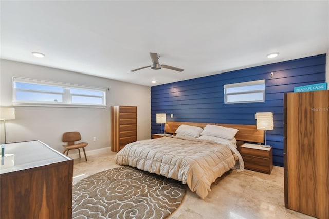 bedroom with ceiling fan and wood walls