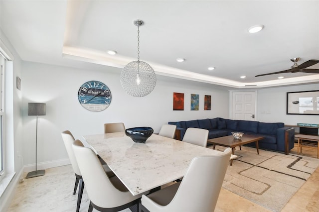 dining space with ceiling fan and a tray ceiling