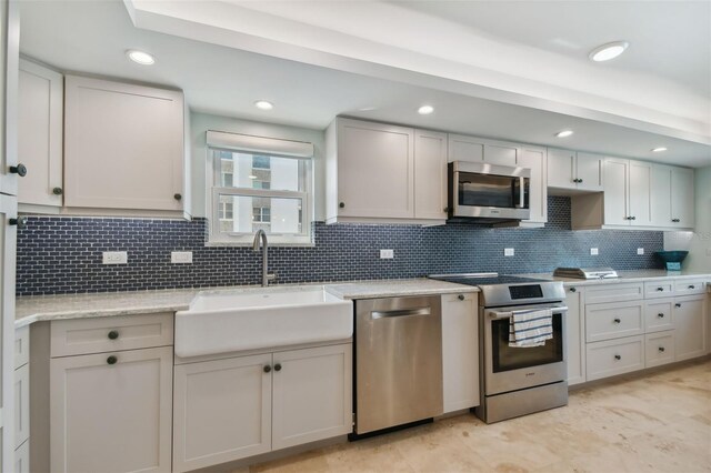 5000 Gulf Blvd Unit 704, St Pete Beach, FL 33706 - kitchen featuring appliances with stainless steel finishes, a sink, backsplash, recessed lighting, and light stone counters