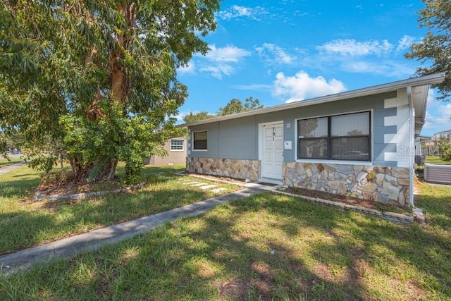 view of front of house with stone siding, central air condition unit, and a front lawn