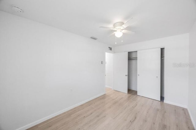 unfurnished bedroom with light hardwood / wood-style flooring, ceiling fan, and a closet