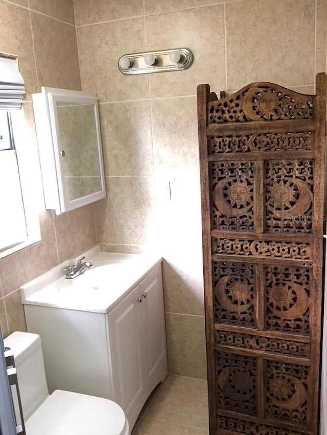 bathroom featuring tile walls, toilet, and vanity