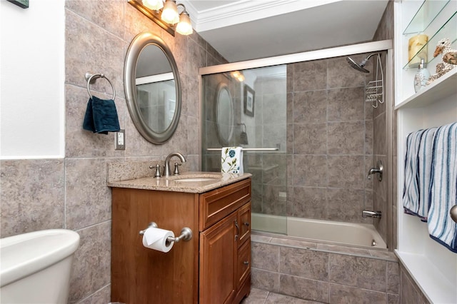 full bathroom with vanity, bath / shower combo with glass door, toilet, ornamental molding, and tile walls