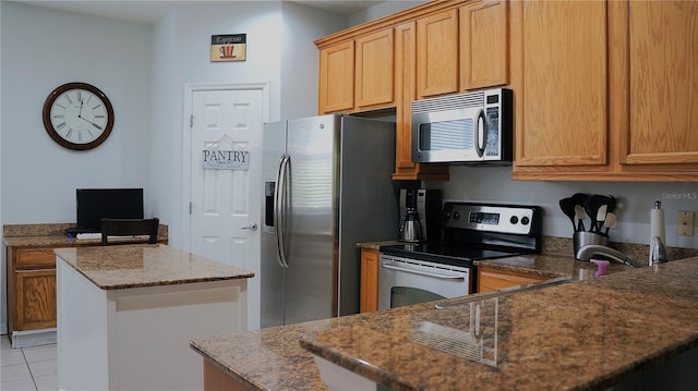 kitchen featuring a kitchen island, stainless steel appliances, stone countertops, and light tile patterned flooring