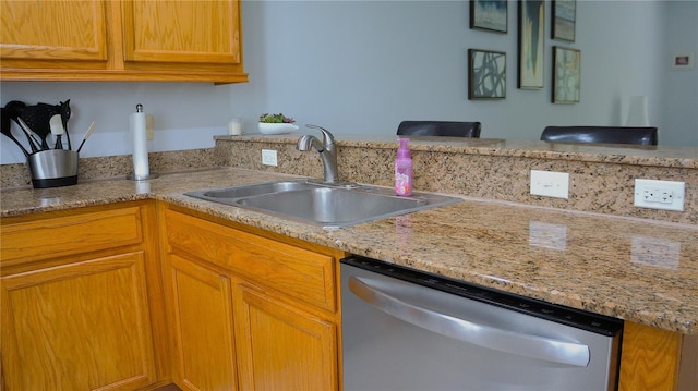 kitchen with dishwasher, light stone counters, and sink