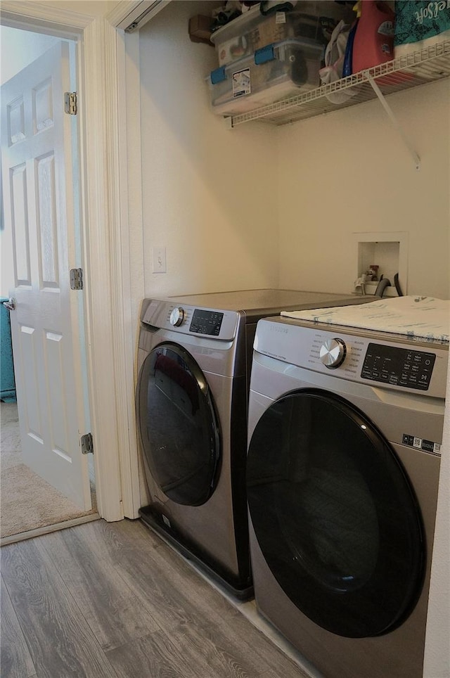 laundry area with washing machine and dryer and wood-type flooring