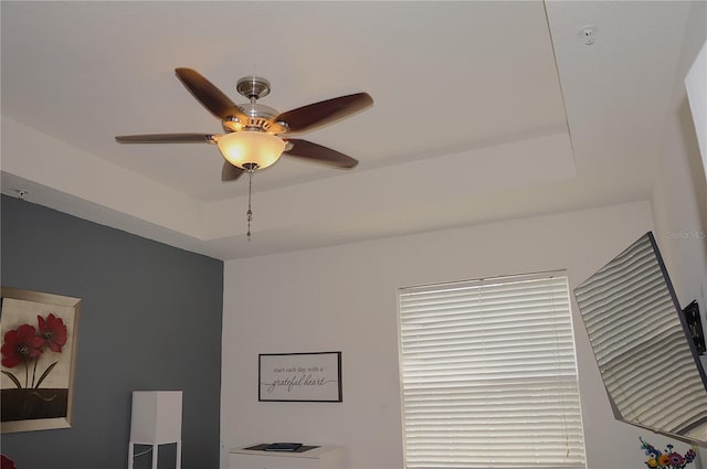 interior details featuring ceiling fan and a raised ceiling