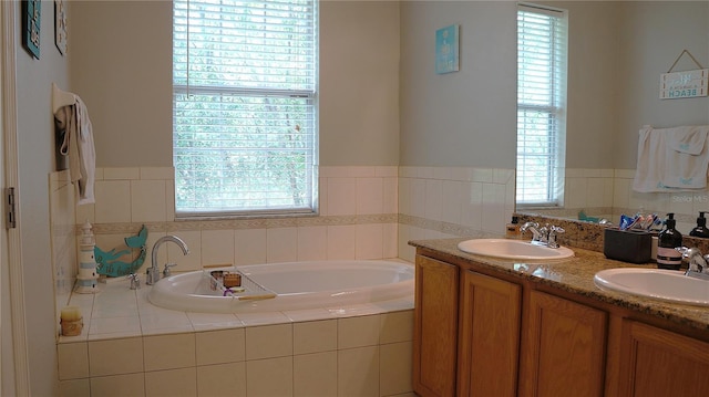 bathroom with a wealth of natural light, tiled tub, and double sink vanity