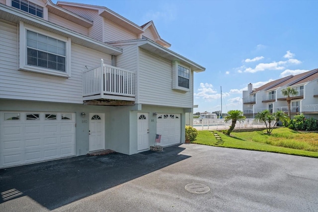 exterior space featuring a garage, a balcony, and a lawn