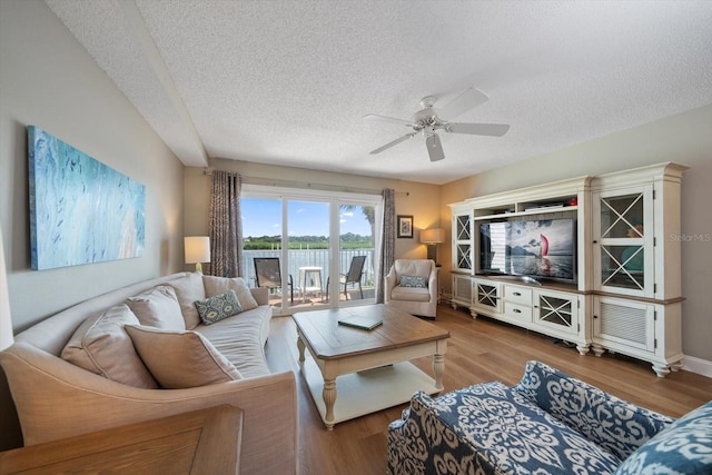 living room featuring a textured ceiling, light hardwood / wood-style flooring, and ceiling fan