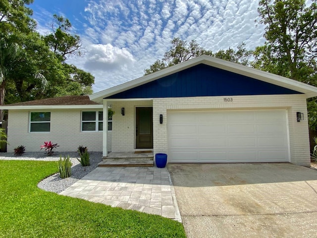 ranch-style home featuring brick siding, a front yard, concrete driveway, and an attached garage