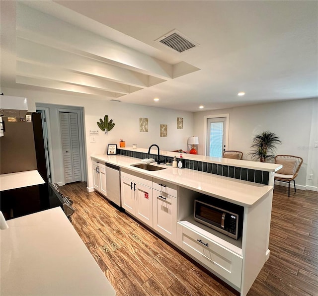 kitchen with white cabinets, a sink, visible vents, stainless steel appliances, and a peninsula