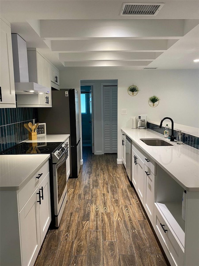 kitchen featuring a sink, stainless steel appliances, visible vents, wall chimney range hood, and white cabinets