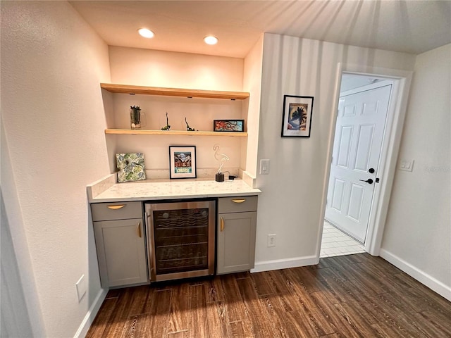 bar featuring a dry bar, beverage cooler, dark wood-style floors, and baseboards