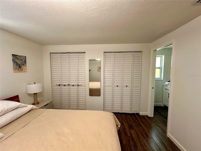 bedroom featuring dark wood-style flooring, multiple closets, a textured ceiling, and baseboards