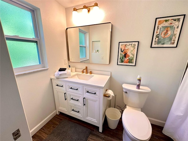 bathroom with wood finished floors, toilet, vanity, and baseboards